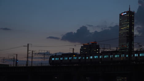 trains crossing hangang on railway bridge and 63 building in background in twilight,yeouido district, yeongdeungpo-gu, seoul, south korea