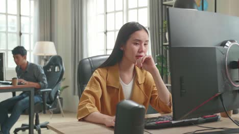 asian female thinking while works on her personal computer in office