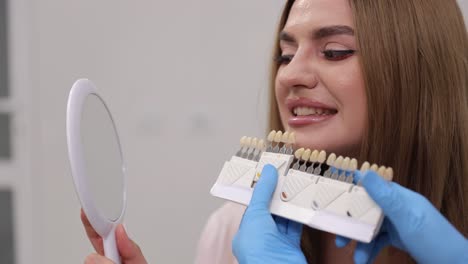 a dental professional provides assistance to a patient in selecting the perfect shade for their teeth color