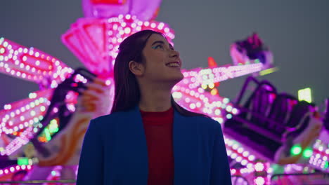 happy girl enjoying amusement park at night. cheerful beautiful model at neon