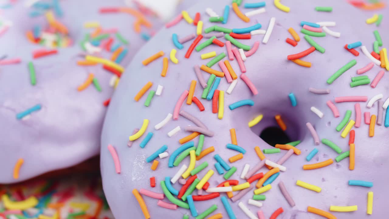 extremo primer plano giratorio colorido caramelo cubierto por anillo de rosquilla de hielo púrpura. cámara roja dragón 4k