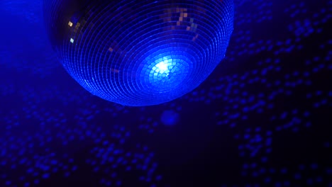imágenes de primer plano de una bola de discoteca de esfera espejada giratoria con reflejos de luces de colores.