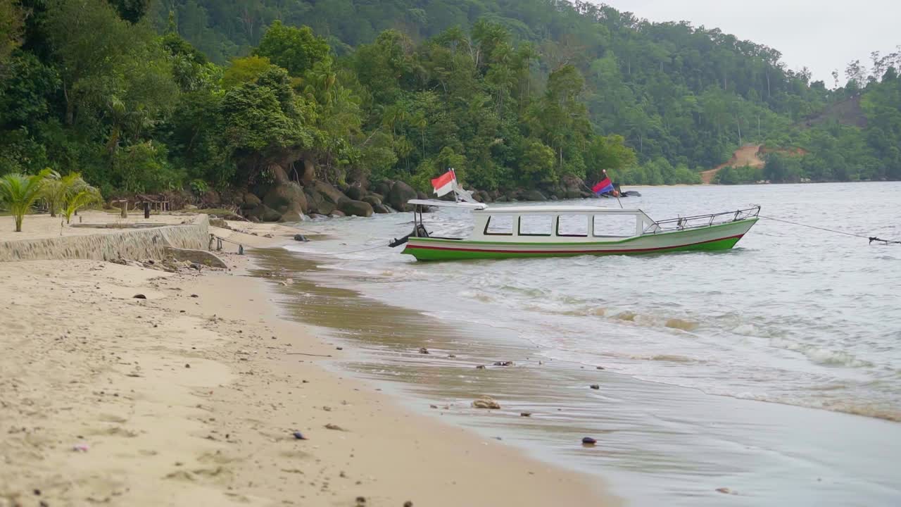 A vibrant traditional Indonesian boat parked on the beach at Sungai Pinang, West Sumatra. The colorful boat and flying Indonesian flag highlight local culture and coastal life.