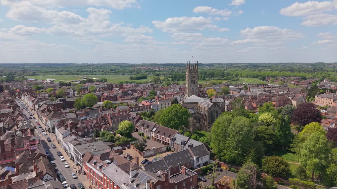 Imágenes orbitales del pueblo de Warwick con la Iglesia de Santa María en el centro, capturadas en un día soleado de primavera con nubes blancas decorando el cielo