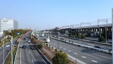 modern highway with cars and trains running in tokyo, japan, bright sunny day