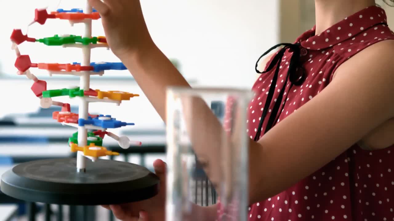 Colegiala atenta experimentando modelo de molécula en laboratorio