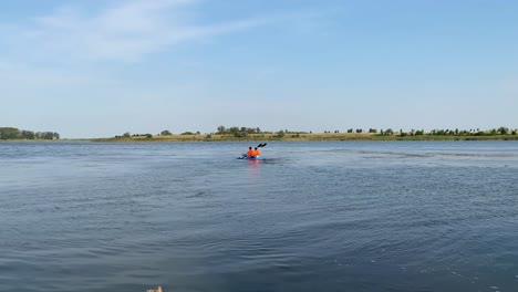 in the middle of the river, one can witness two individuals maneuvering the kayak