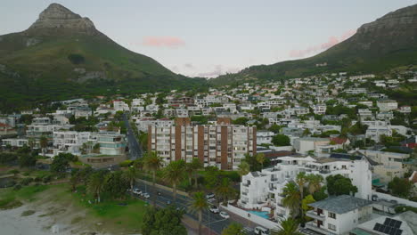 Aerial-footage-of-apartment-buildings-and-guesthouses-in-tropical-travel-destination.-Rock-mountains-and-pass-between-in-background.-Cape-Town,-South-Africa