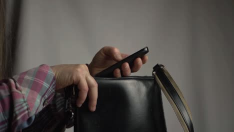 Woman-getting-cellphone-out-of-handbag-medium-shot
