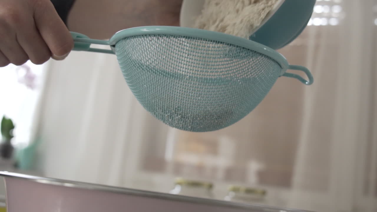 Slow motion as pouring flour through a sift, sifting flour preparation to bake as an ingredient