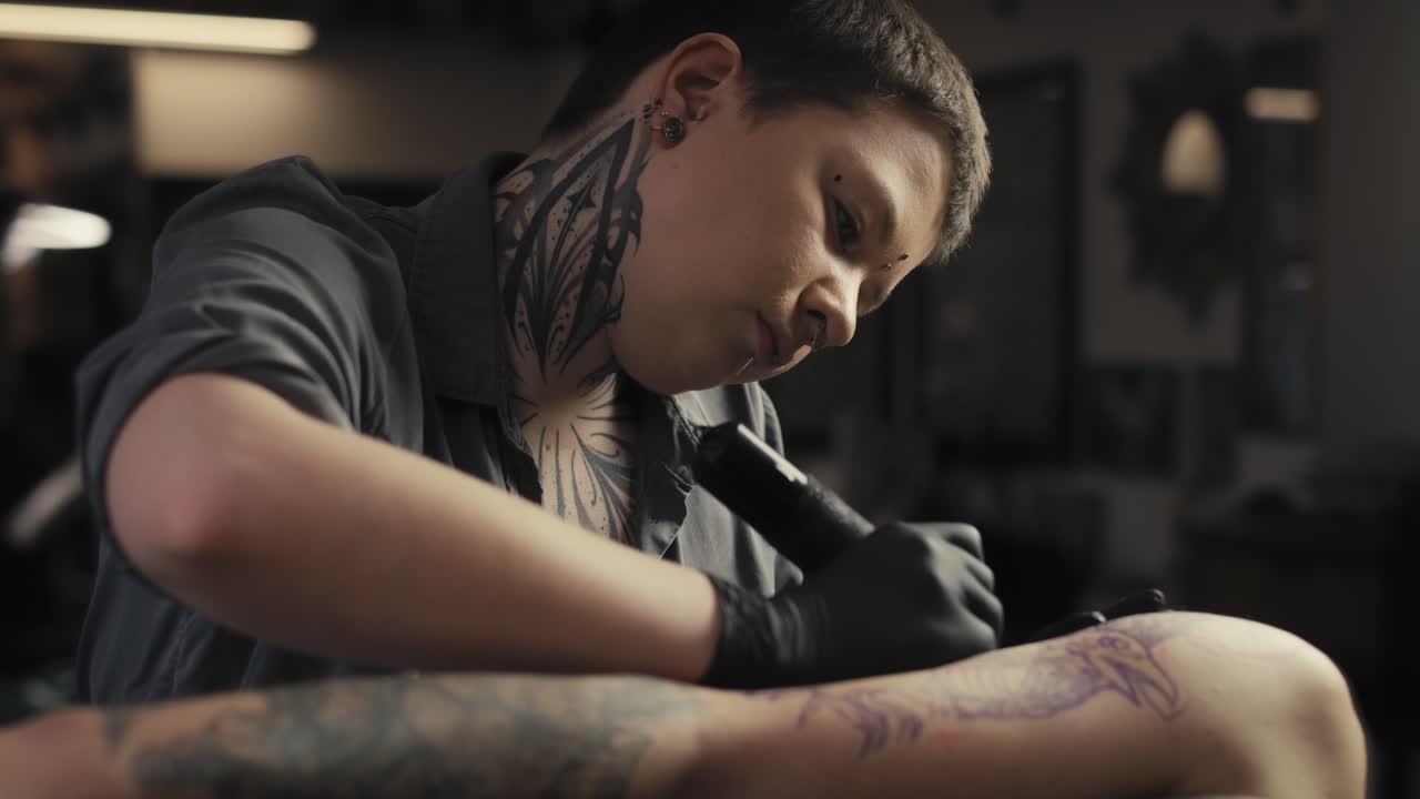 Focus caucasian woman tattooing arms of her customer.