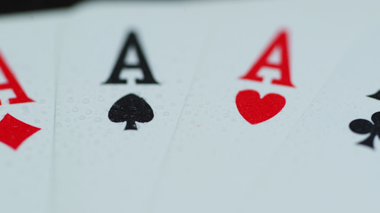 Macro of a shot of playing cards with all four aces hearths diamonds space cross lying on an elephant while moving when the cards are splashed with water leaving a drop of detail