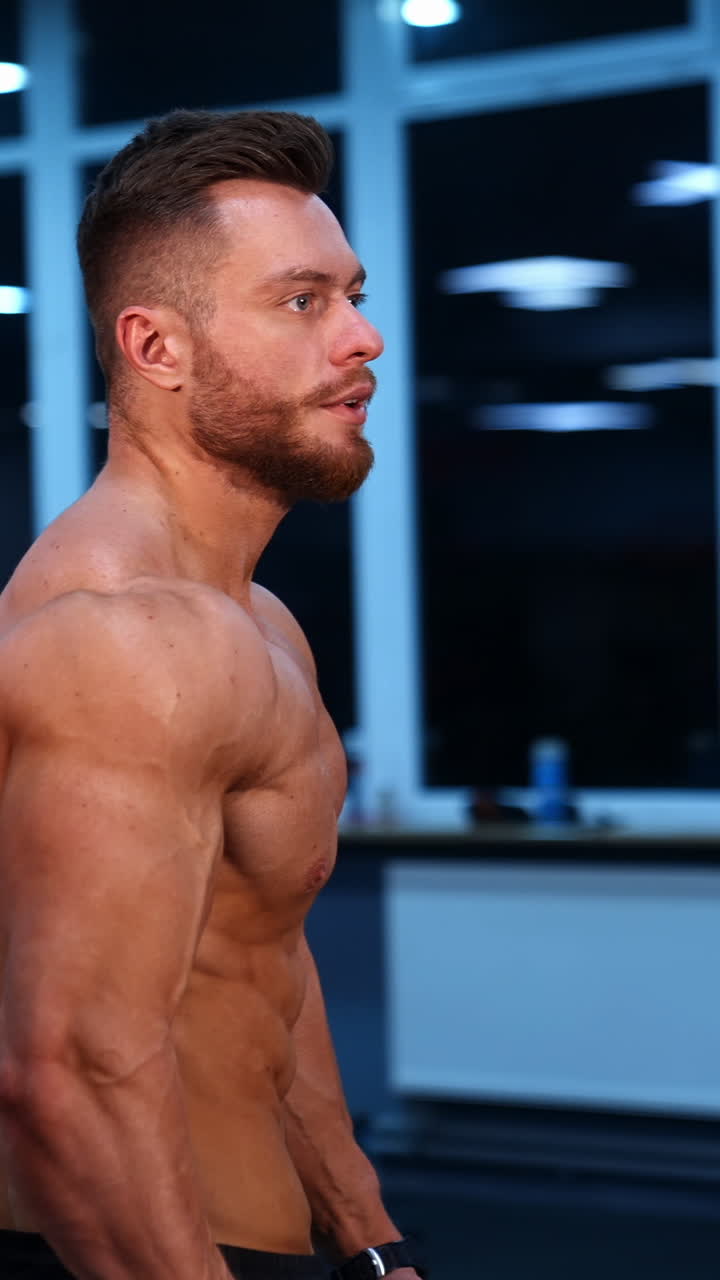 Strong athletic man in sports center. Muscular bodybuilder showing his naked torso in gym. Handsome shirtless sportsman with athletic body. Vertical video