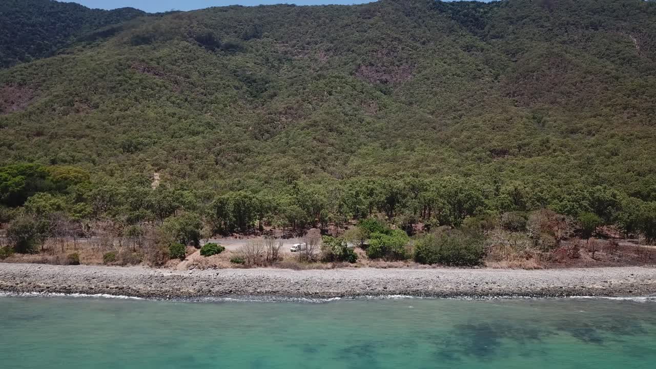 Drone moving up and pan down over tropical beach and mountainside