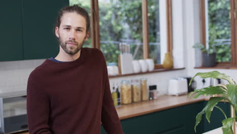 Portrait-of-happy-caucasian-man-using-smartphone-in-kitchen-at-home,-slow-motion,-copy-space