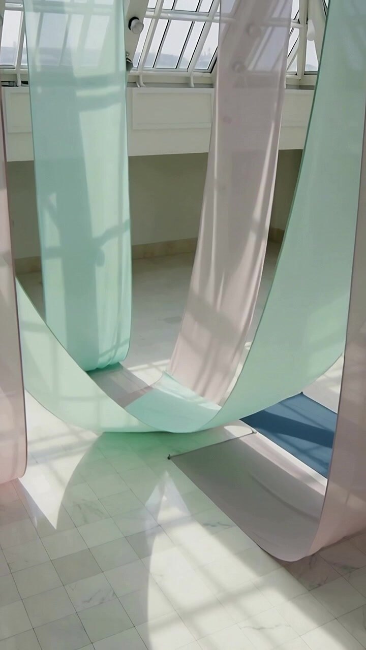 Vertical video: Billowing sheer panels swaying from skylight in atrium, soft breeze moving them