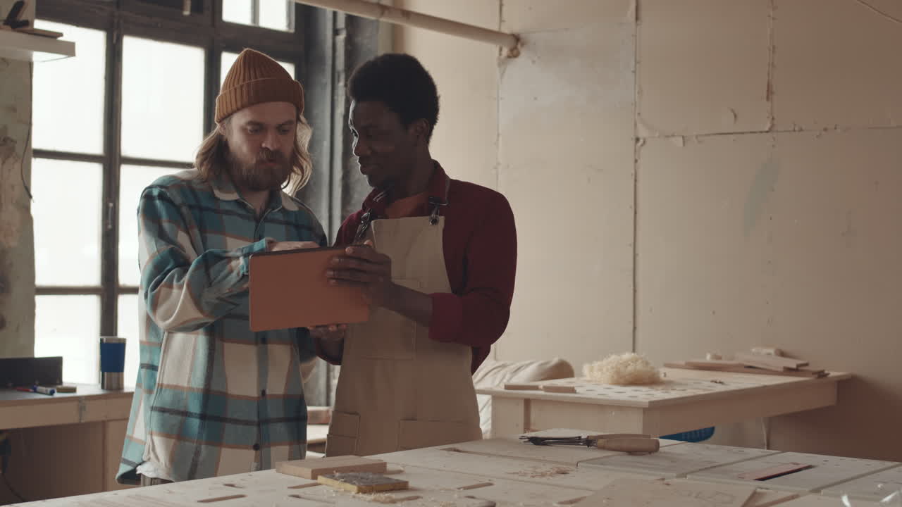 Two Diverse Men Using Digital Tablet in Workshop