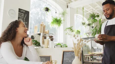 Glücklicher-Afroamerikanischer-Männlicher-Barista,-Der-Im-Café-Kaffee-Biracial-Weiblichen-Kunden-Serviert