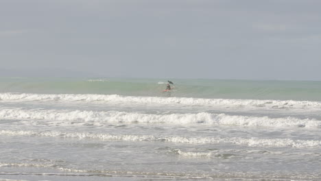 surfers catching waves out in the ocean in castle point, new zealand