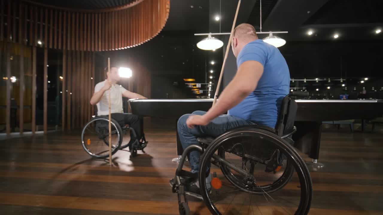 Adult men with disabilities in a wheelchair play billiards in the club