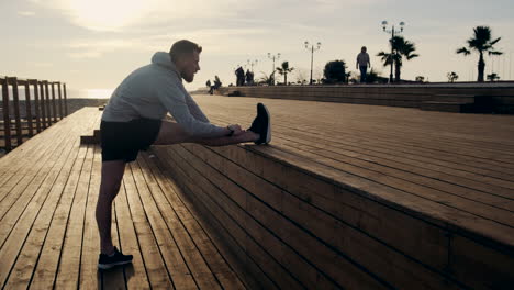 hombre estirándose en un muelle de madera al amanecer o al atardecer