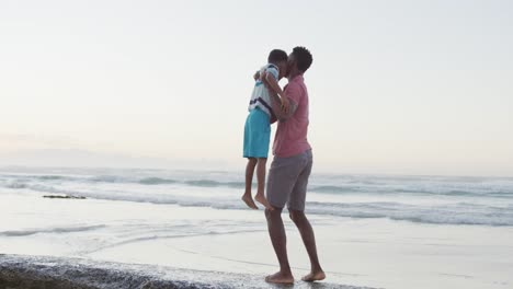 African-american-father-carrying-his-son-on-sunny-beach