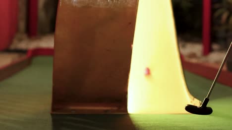 a mini golf ball approaches a glowing ramp, highlighting the precision of the putt.