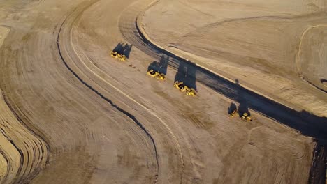 Drone-aerial-footage-of-excavator-scraping-machines-in-the-desert-at-sunset