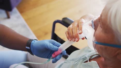 Video-of-hands-of-african-american-male-doctor-keeping-oxygen-to-caucasian-senior-woman