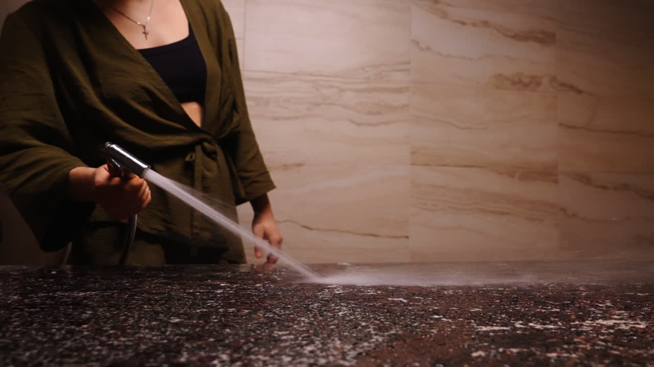 Woman Cleaning a Bathroom Countertop with a Shower Head