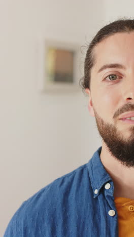 vertical video of half face of happy caucasian man with beard standing and smiling on sunny house