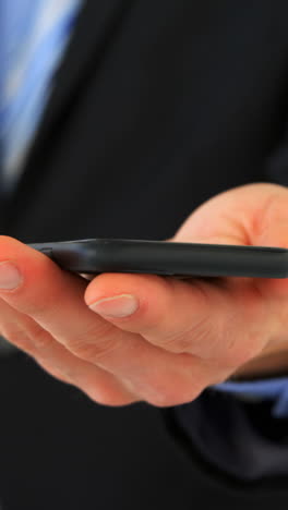 mid section of businessman text messaging on mobile phone