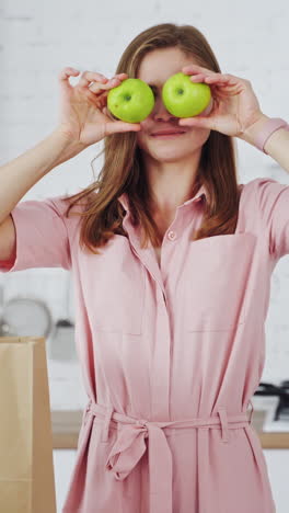 woman in modern kitchen. adorable girl having fun with apple in modern light white kitchen vertical video