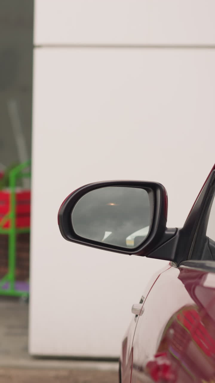 mujer elegante con bolso de cuero en el hombro cierra la puerta del coche con la mano caminando lejos. automóvil rojo estacionado cerca del edificio de oficinas closeup cámara lenta