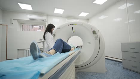 female patient is undergoing ct or mri scan under supervision of a radiologist in modern medical clinic. patient lying on a ct or mri scan bed, moving outside the machine.