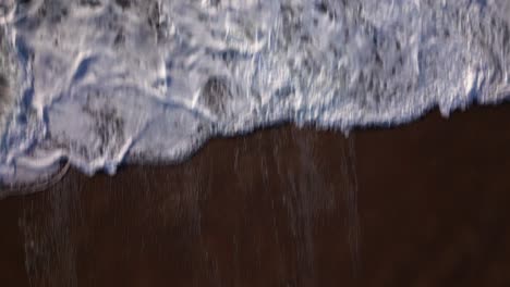 la cámara de un avión no tripulado que vuela desde una playa de arena revela las tormentosas olas del océano