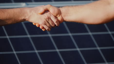 handshake of two men on the background of solar panels