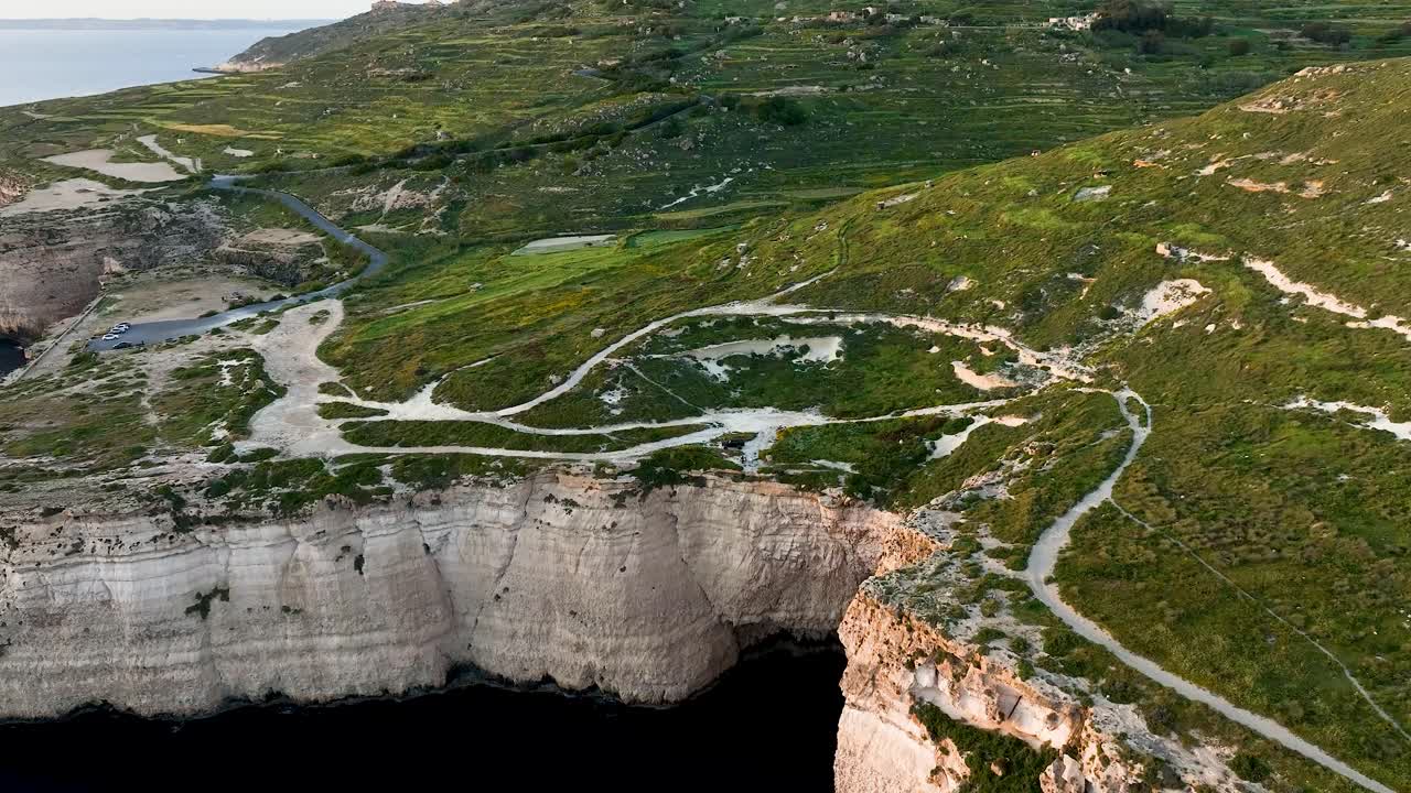 Experience the awe-inspiring vertical cliffs of Miġra l-Ferħa, where sheer rock faces meet the deep blue sea and rolling countryside, filmed in crisp 4K from above.