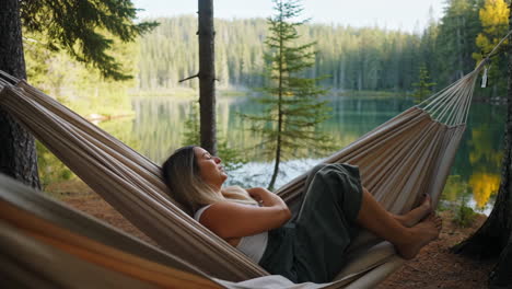 woman relaxing in a hammock by a serene forest lake