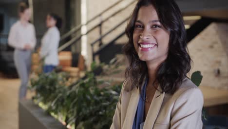 portrait of happy biracial casual businesswoman in office lounge with copy space, slow motion