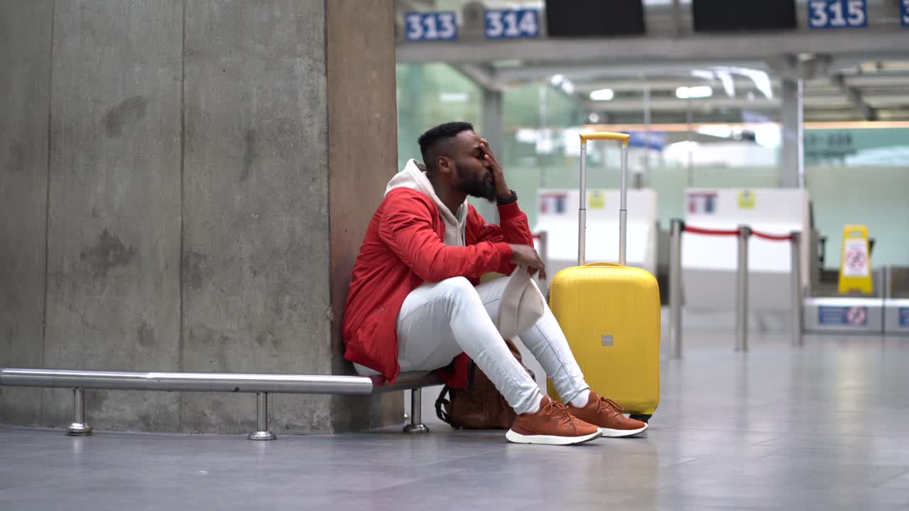 hombre turista negro cansado en una larga conexión nocturna en el aeropuerto, esperando el avión sentado en la terminal