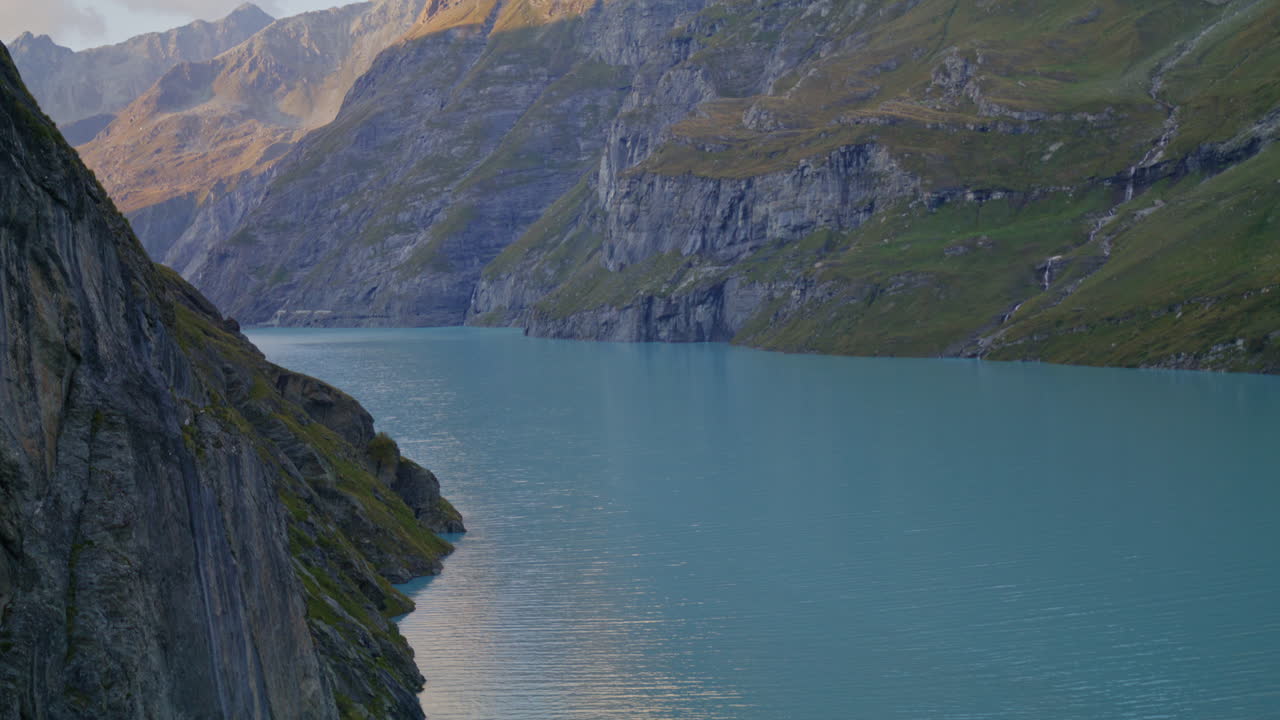 Peaceful summer hike in the Swiss Alps near Mauvoisin, Val de Bagnes, with a border collie enjoying nature, alpine trails, and the turquoise Lac de Mauvoisin under clear blue skies.