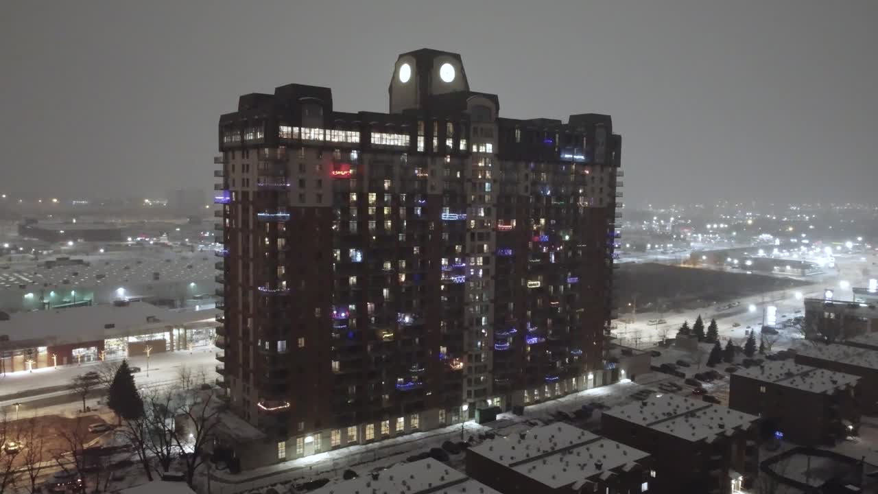 Night view of a brightly lit building in Laval, Quebec, snow covered streets and city lights