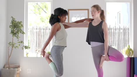 felices y diversas niñas adolescentes haciendo ejercicio y estirándose en una habitación blanca, en cámara lenta.