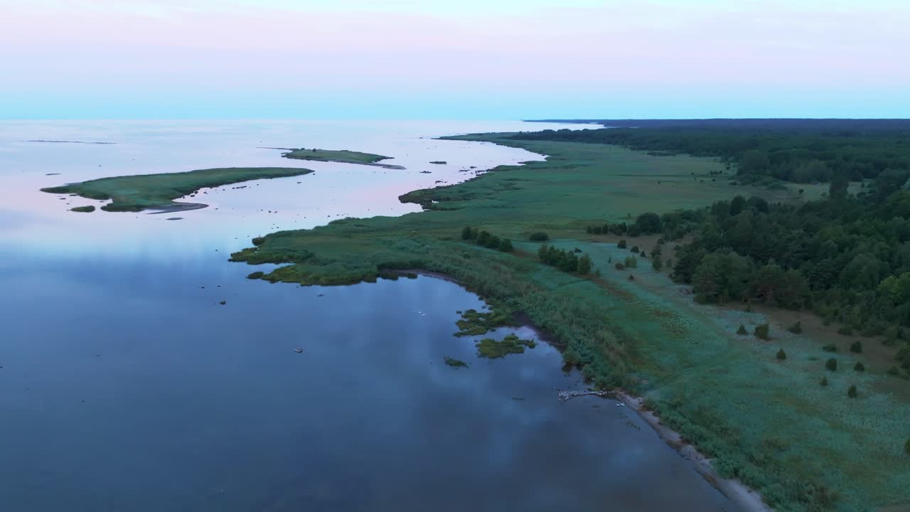 Flying over calm sea and green coastline during evening hours, two islands in the sea