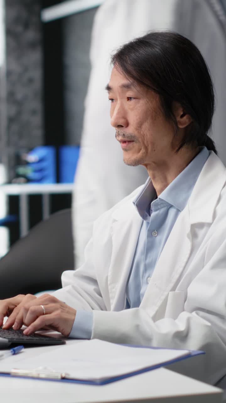 Vertical video Senior laboratory scientist feeling neck ache while using PC to log patient data