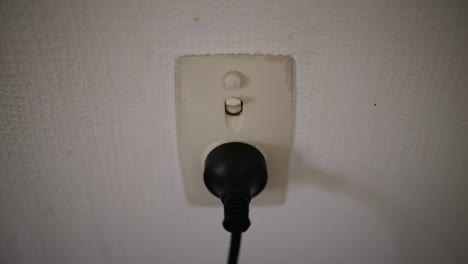 hand switching off oceanic power point with black plug in it