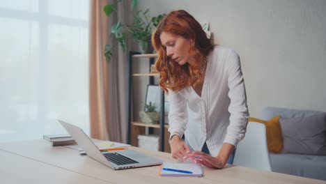 caucasian student woman taking notes in notebook from laptop