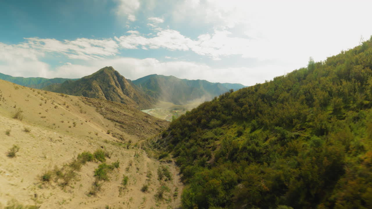 Chasm carves divide between mountains fpv. Dense forest with trails etched upon slopes creating scene of stark natural beauty. Picturesque landscape