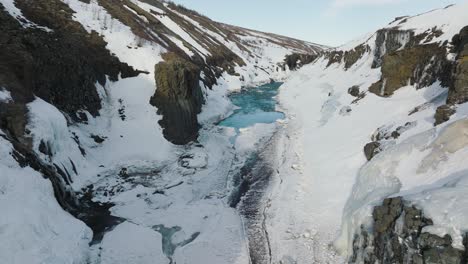 snowy tall cliffs of studlagil canyon during iceland winter - aerial